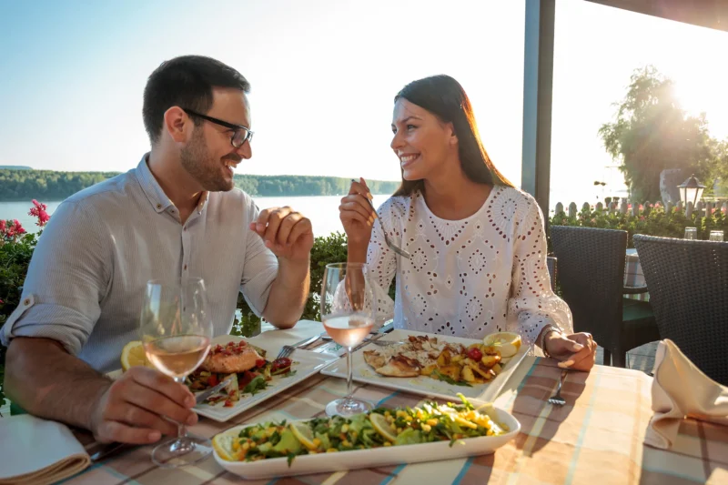 Couple eating at restaurant sitting outside overlooking lake